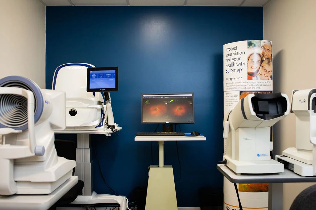 Diagnostic instruments in the exam area at New Vision Optometry, arranged against the practice's cobalt wall