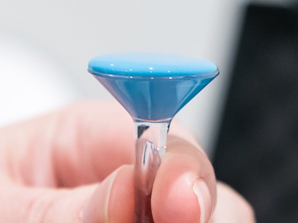 An EyePrint mold held between the fingers, the blue impression on its clear stem