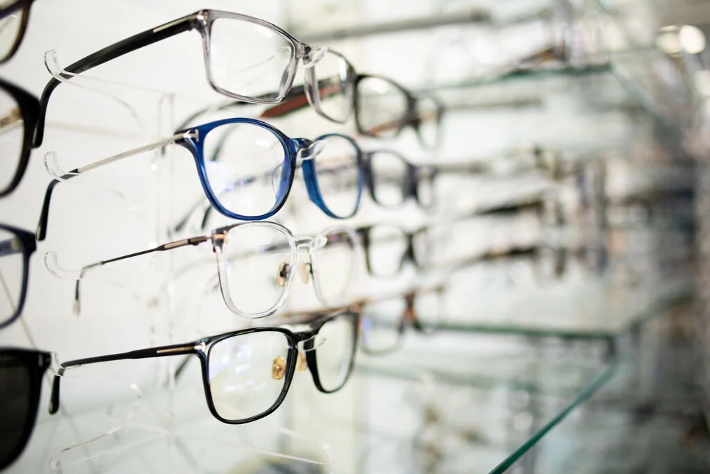 A close view of eyeglass frames on a display rod at New Vision Optometry, black, clear and navy acetates in a row
