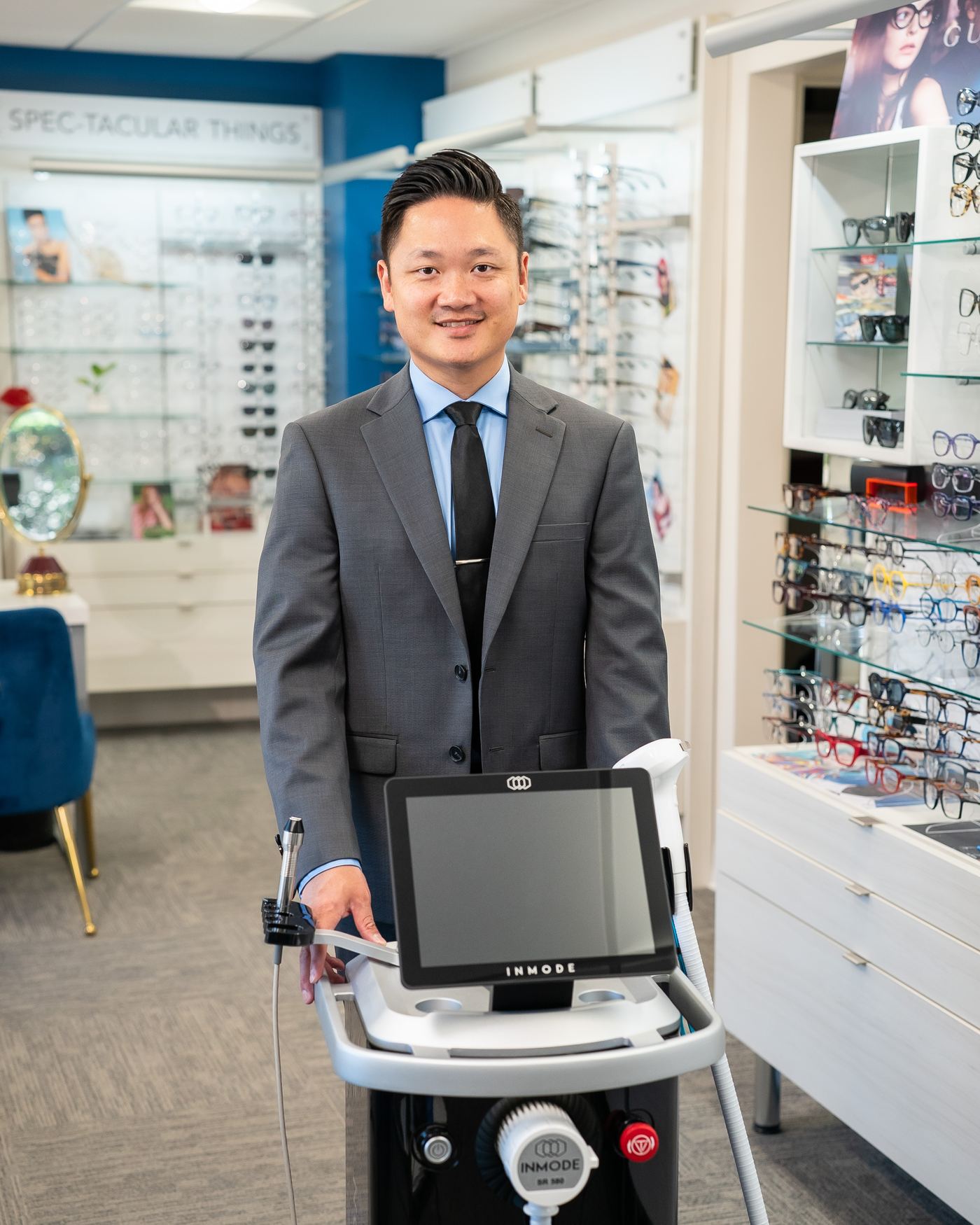 Dr. Long Nguyen, O.D., in a dark suit, standing in the optical at New Vision Optometry