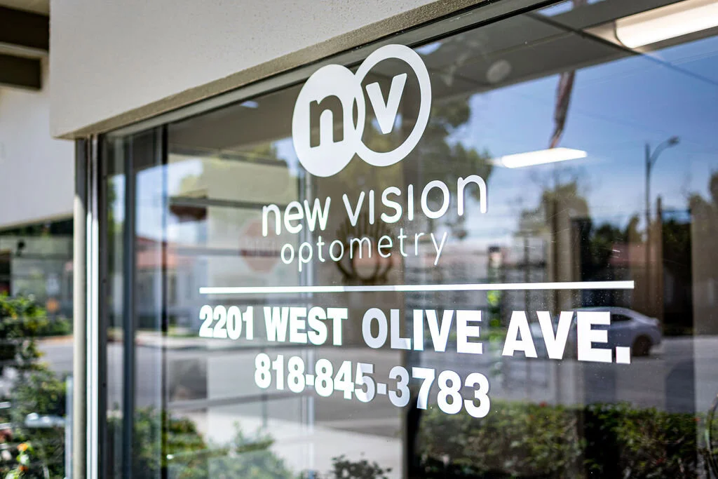 The New Vision Optometry storefront on West Olive Avenue in Burbank, the practice logo and the street address painted on the window glass